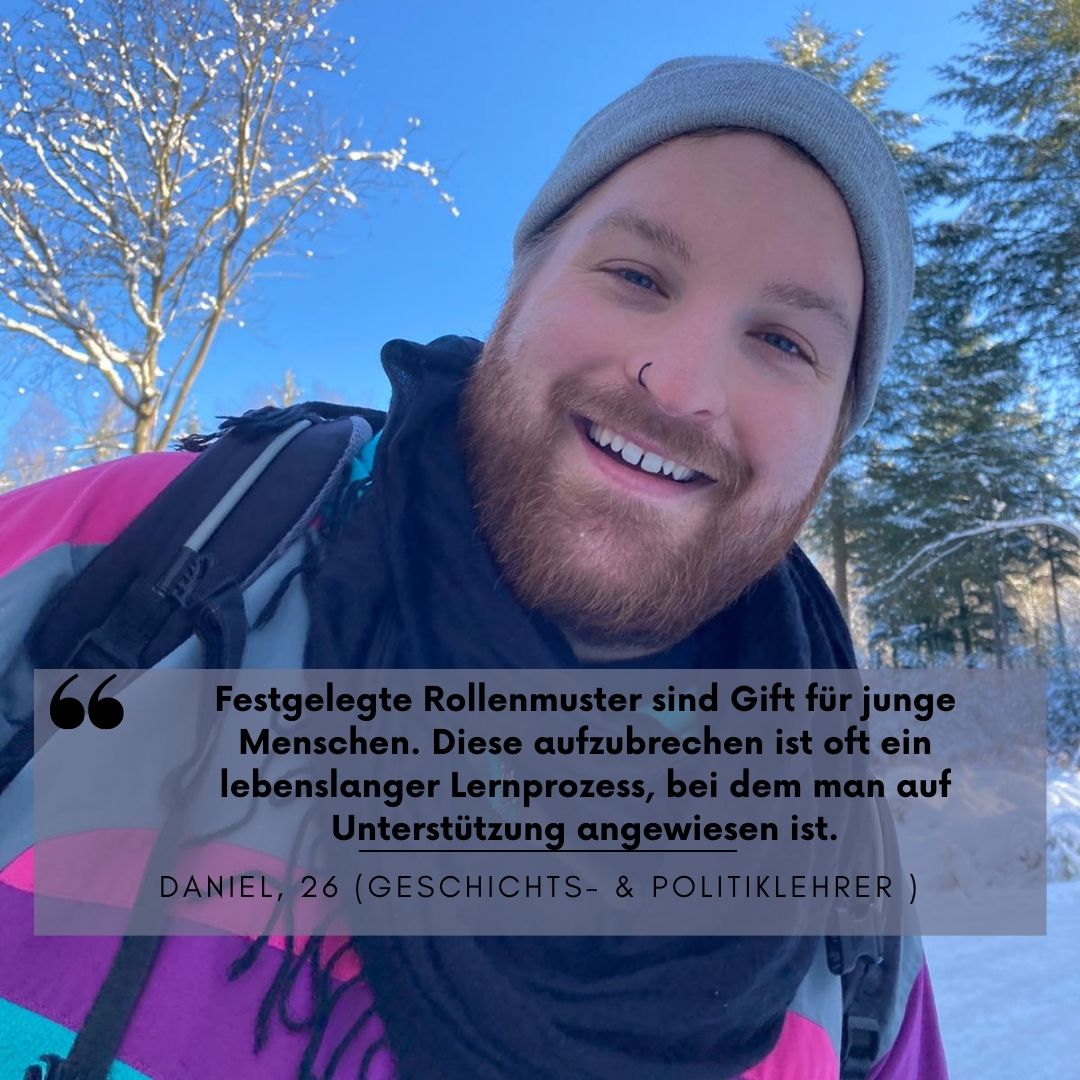 Ein Mann in Ski-Kleidung steht in einer Winterlandschaft und lacht breit. 