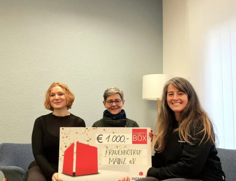 Leah Krieger (l.) und Eva Jochmann (m.) vom Frauennotruf Mainz bei der symbolischen Spendenübergabe von Marta Wojcik (r., DATAGROUP)